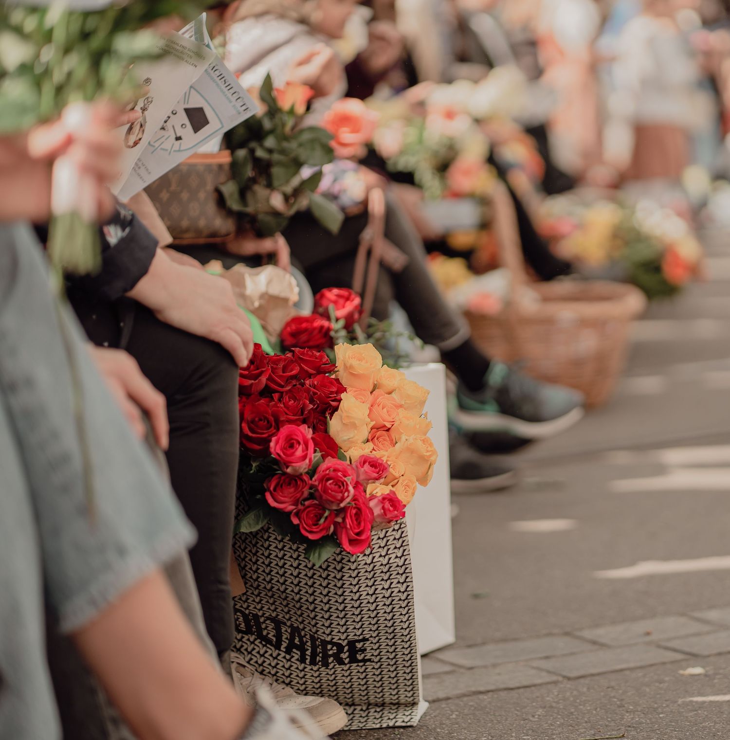 Colorful red and orange roses displayed in a bag at an outdoor flower market.