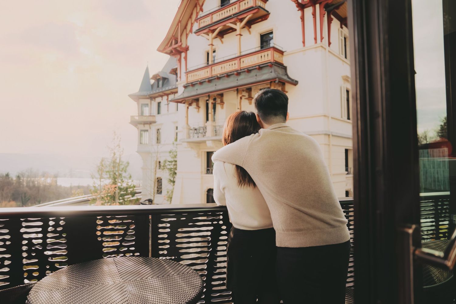 Couple embracing on a balcony overlooking a beautiful historic European-style building.
