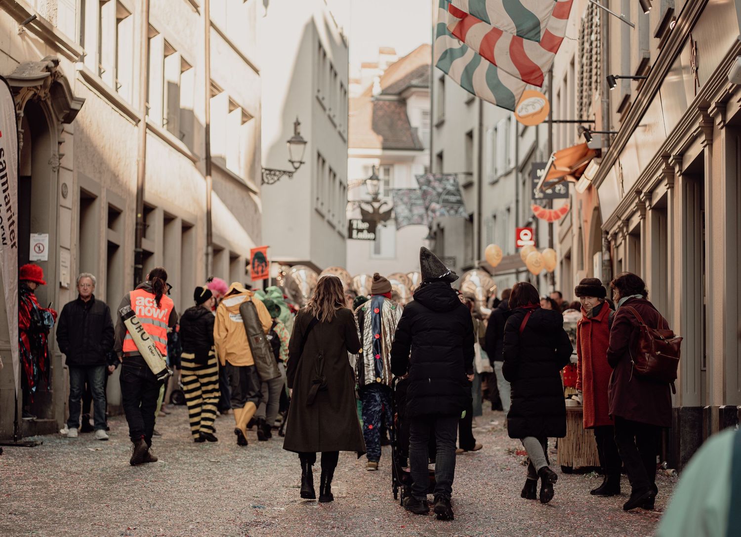 Crowd walking through narrow European old town street during carnival festival.