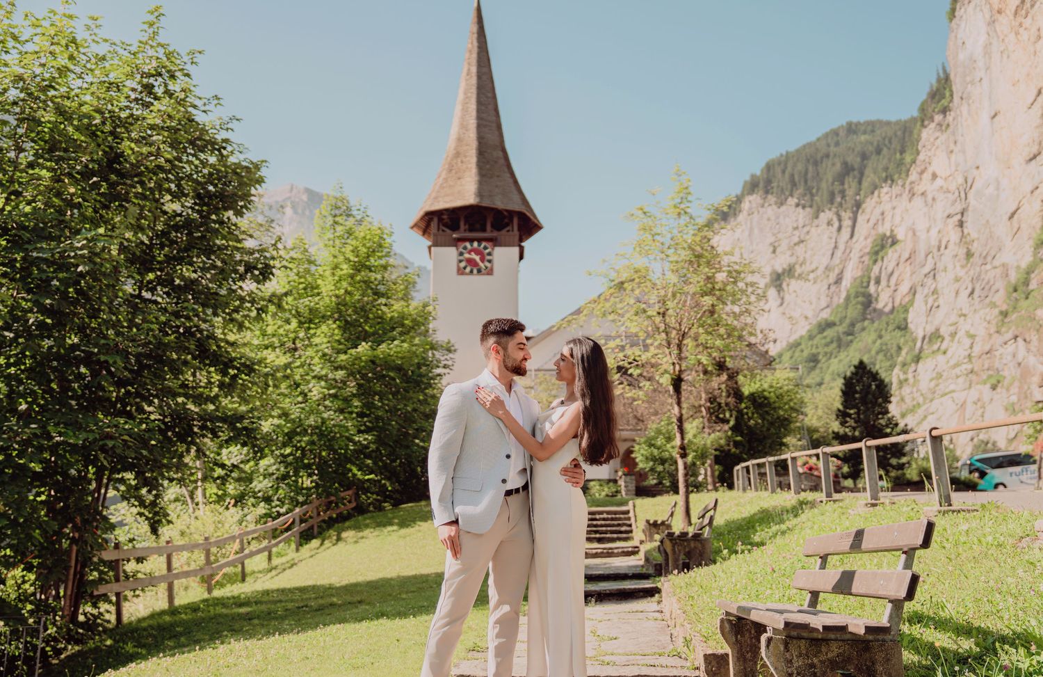Couple dancing near a rustic church tower surrounded by Swiss alpine scenery.