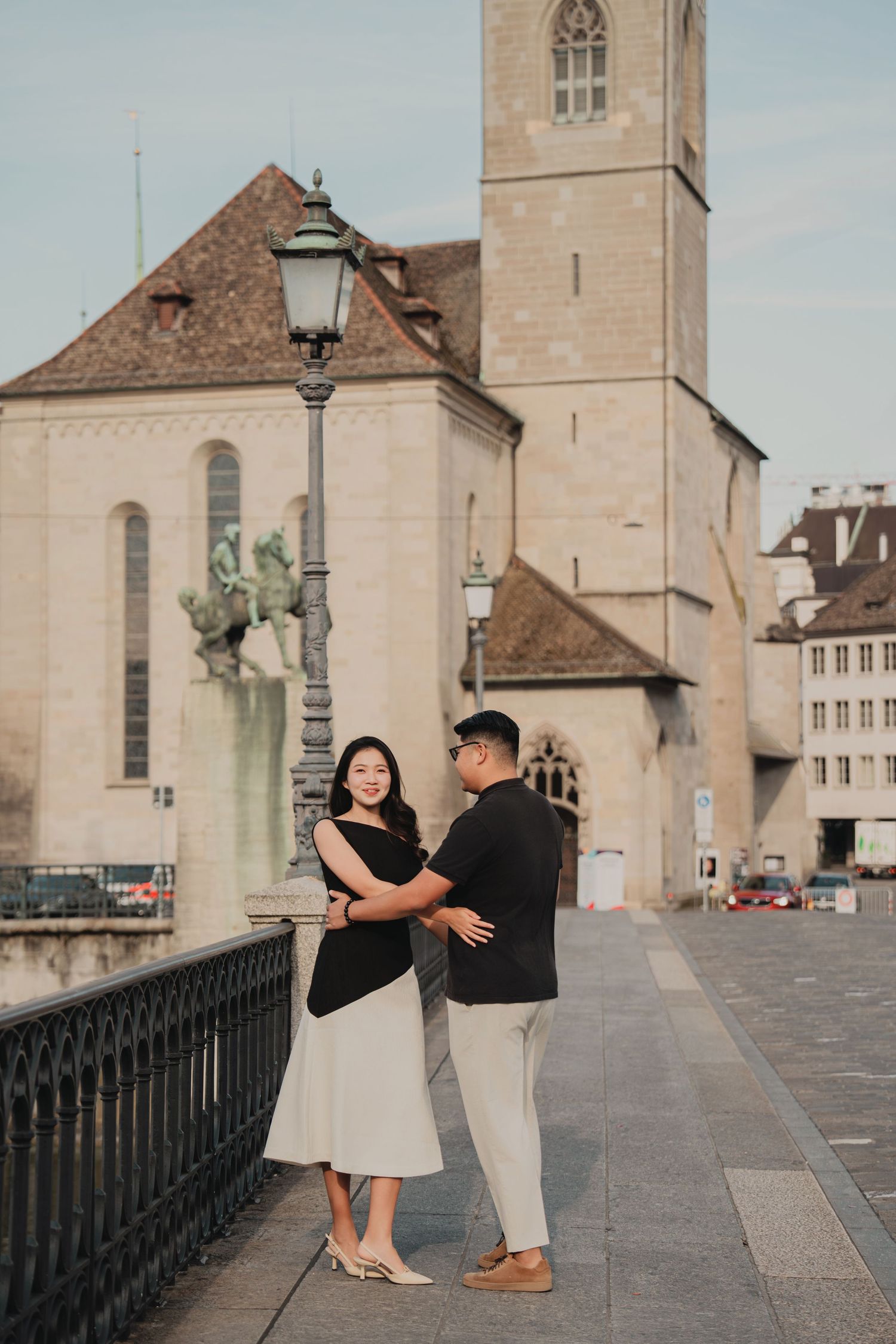 Couple sharing a romantic moment near a lamppost with Grossmunster church in Zurich's old town.