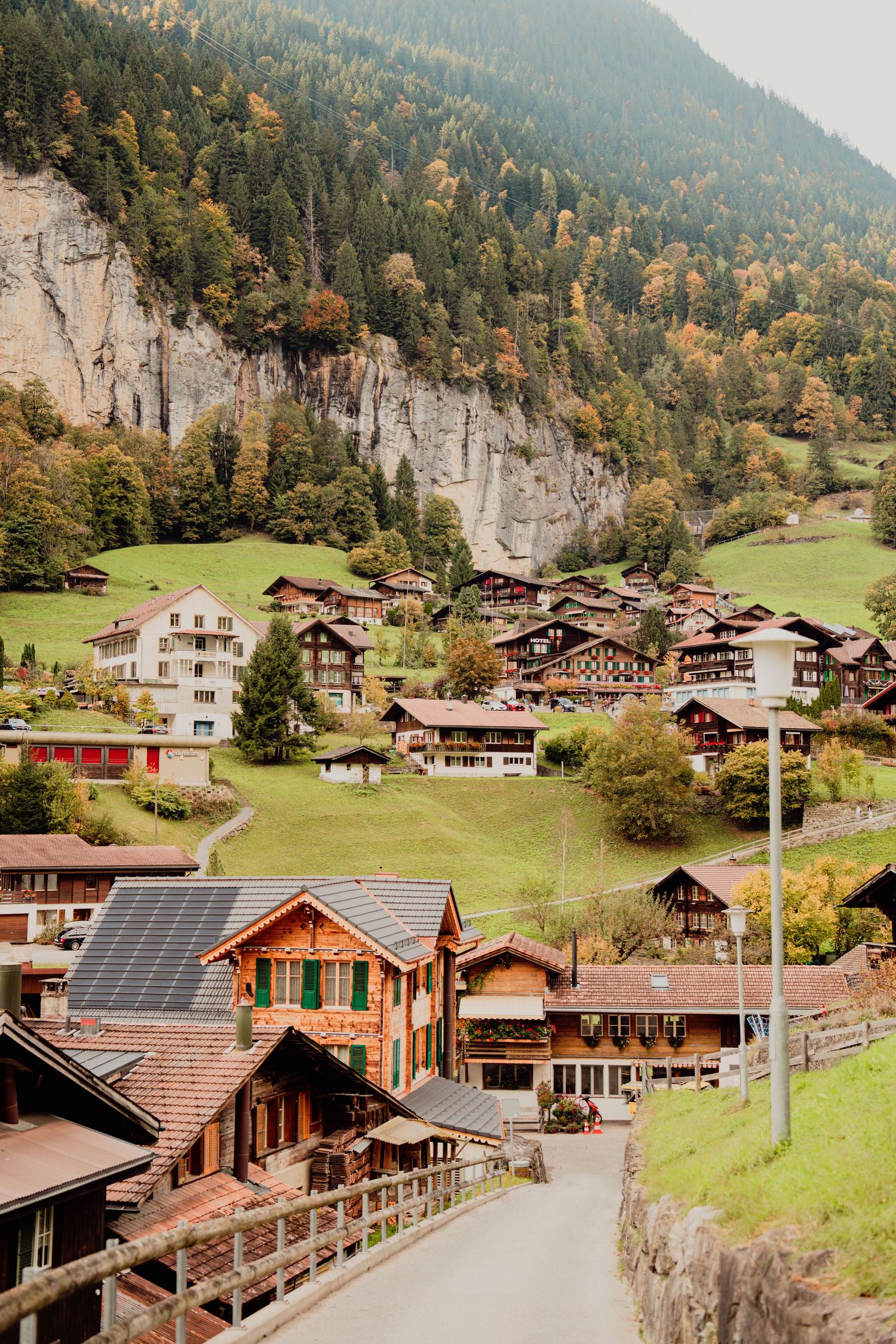Picturesque Swiss alpine village with traditional wooden chalets nestled against a forested mountain.