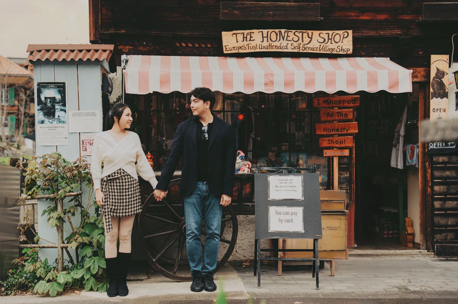 Young couple holding hands outside a vintage homesty shop with striped awning.
