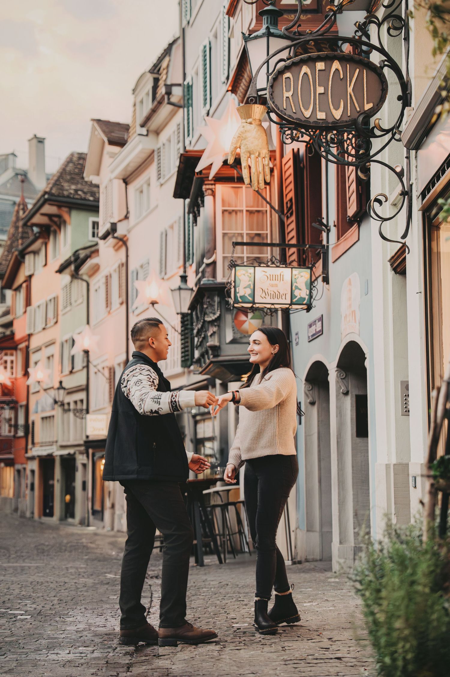 Joyful couple exchanging gifts on a scenic cobblestone street in Zurich's historic old town.