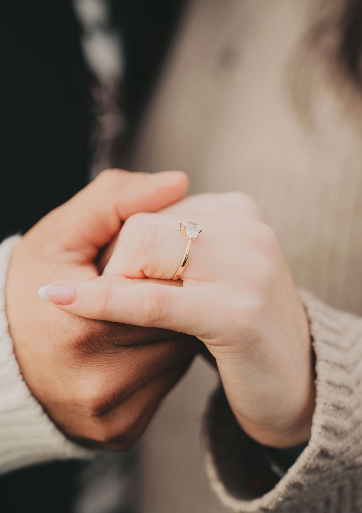 Close-up of couple holding hands displaying a beautiful heart-shaped diamond engagement ring.