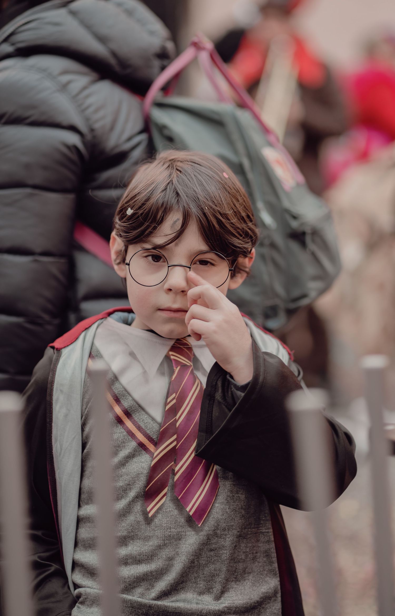 Child dressed as Harry Potter with round glasses and Gryffindor tie at a carnival.