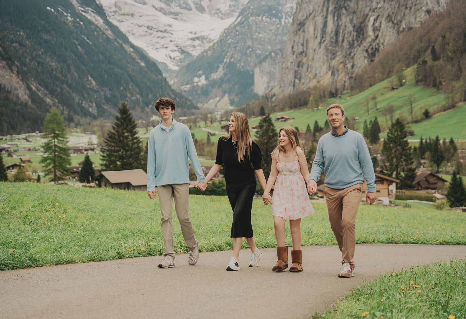 Family of four enjoying a leisurely walk on a path in picturesque Lauterbrunnen, Switzerland.