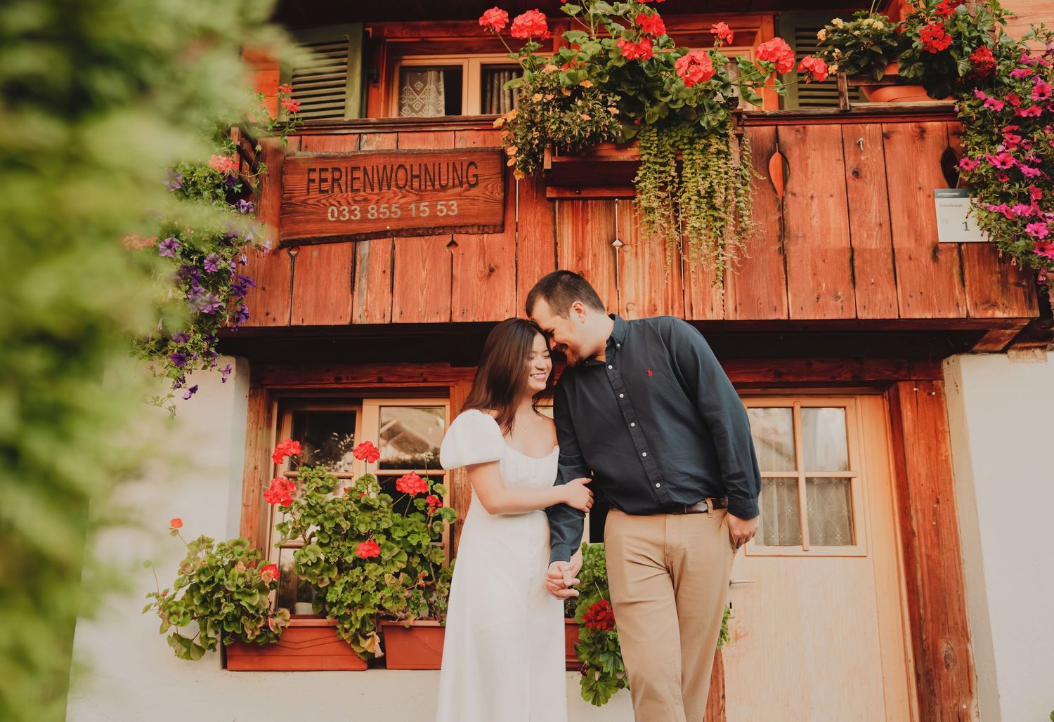 Couple sharing a tender moment outside a flower-decorated Swiss Ferienwohnung chalet.