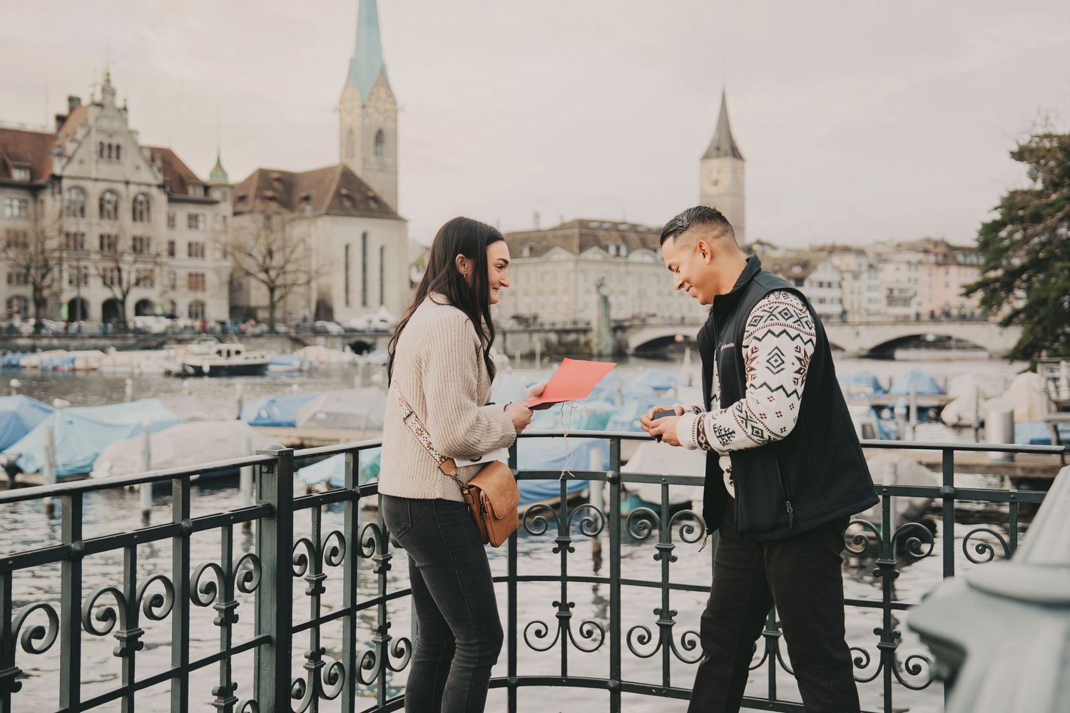 Couple sharing a romantic moment on a bridge overlooking the beautiful Zurich waterfront cityscape.