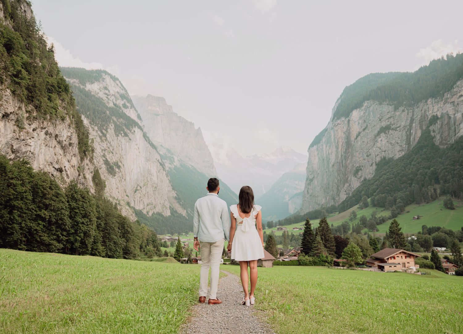 Couple walking hand in hand toward the breathtaking Lauterbrunnen valley in the Swiss Alps.