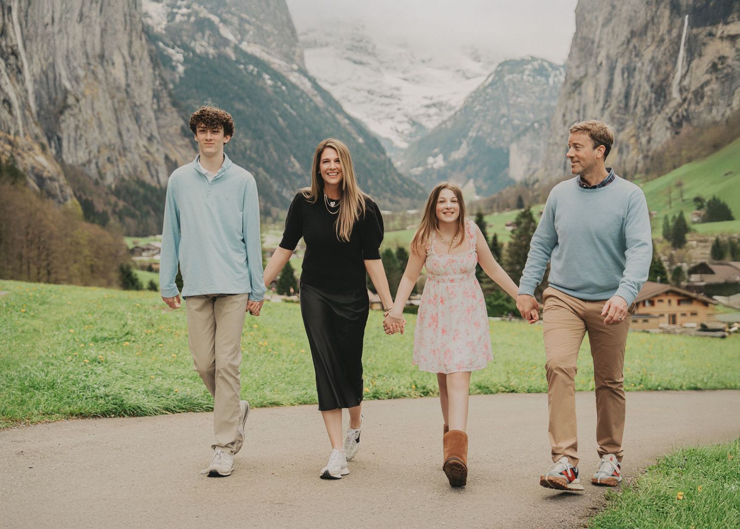 Happy family holding hands while strolling through the stunning Swiss Alps village of Lauterbrunnen.