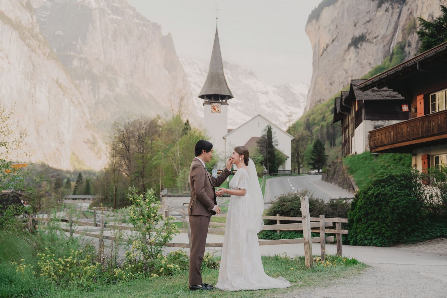 Bride and groom facing each other in a romantic exchange near a Swiss church in Lauterbrunnen valley.