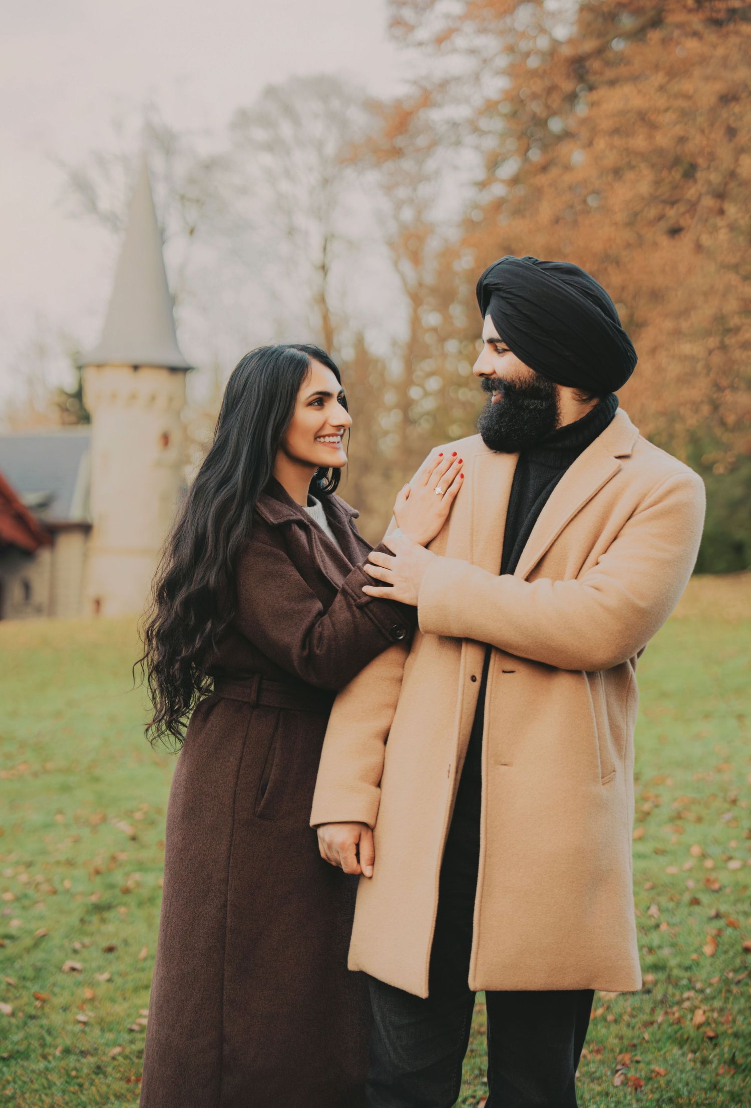 Happy couple sharing a tender moment with a castle tower visible in the autumn background.