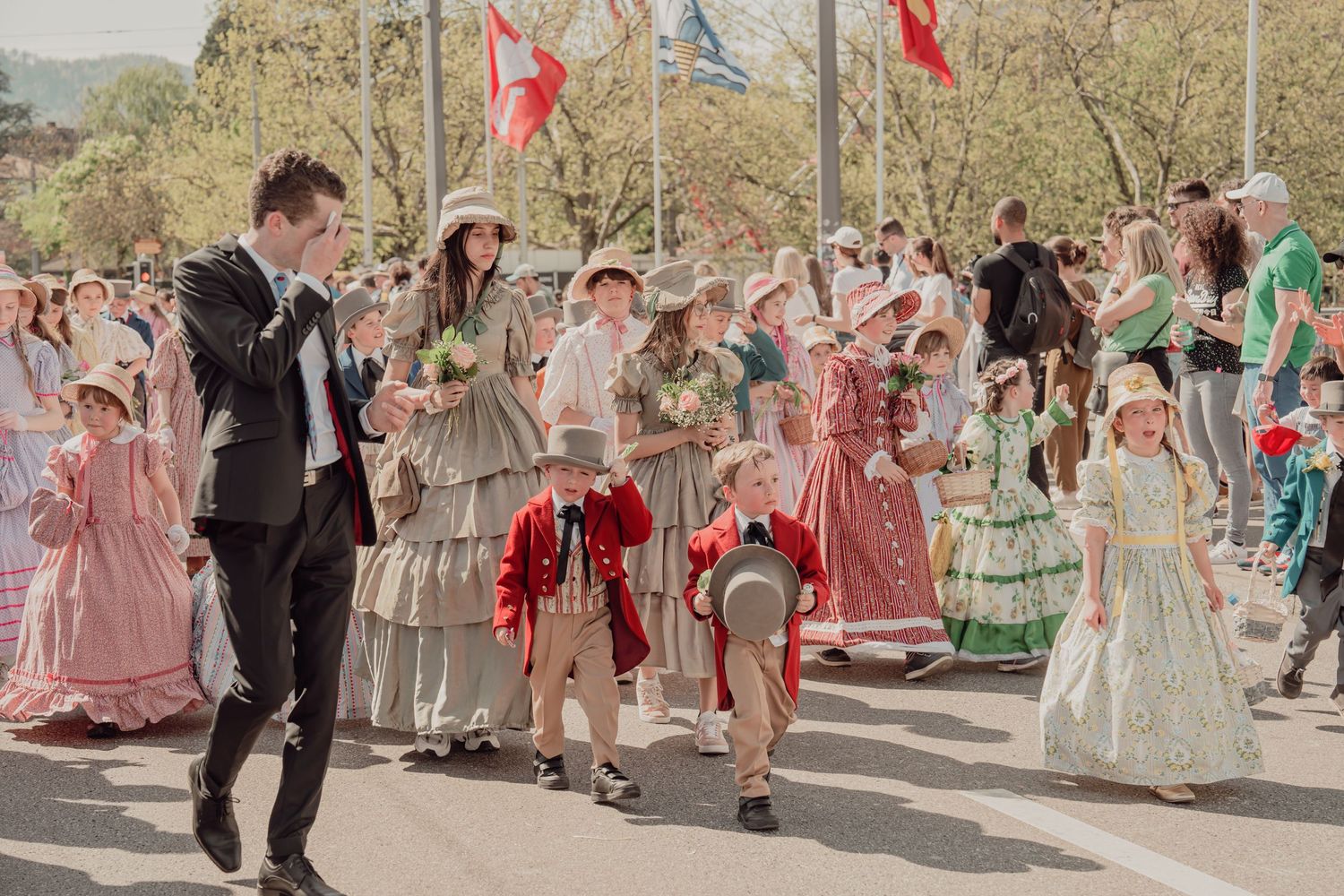 People dressed in elegant historical costumes participate in a colorful outdoor parade celebration.