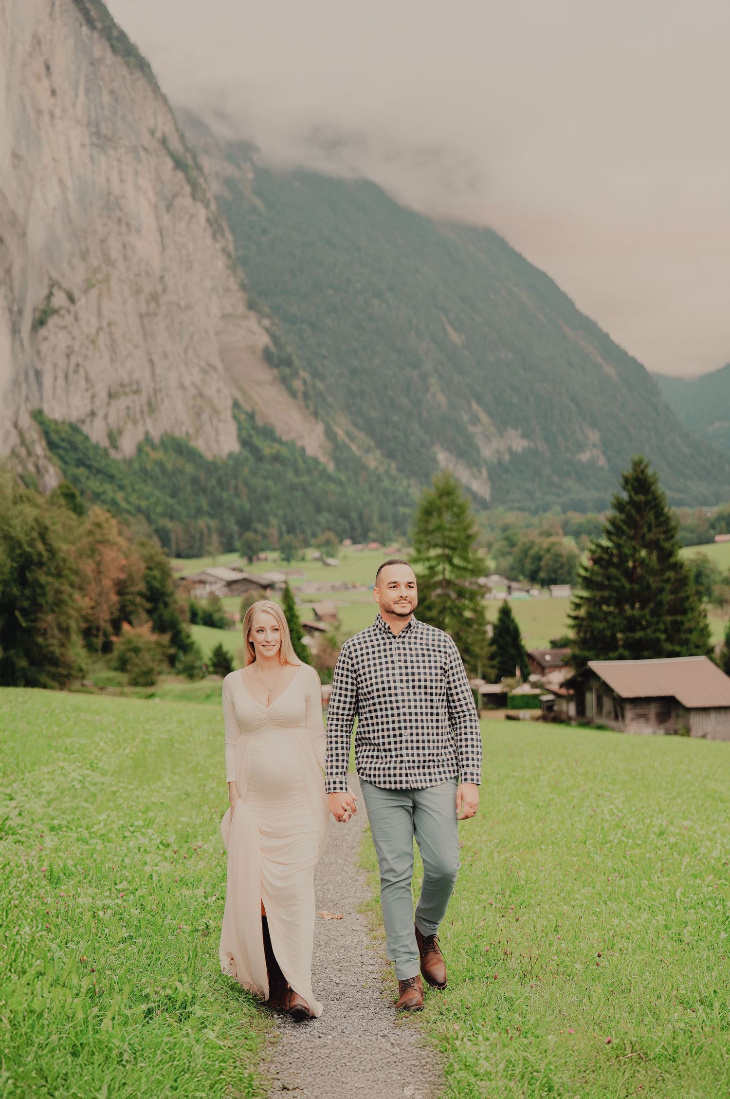Happy couple holding hands walking on scenic mountain path in Lauterbrunnen valley Switzerland.