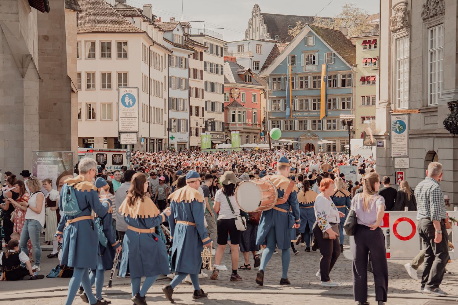 Large crowd gathering in historic Zurich town square during traditional street festival.
