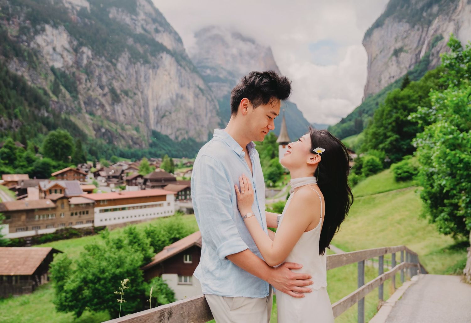Romantic couple embracing and almost kissing on a bridge overlooking Lauterbrunnen village in Switzerland.
