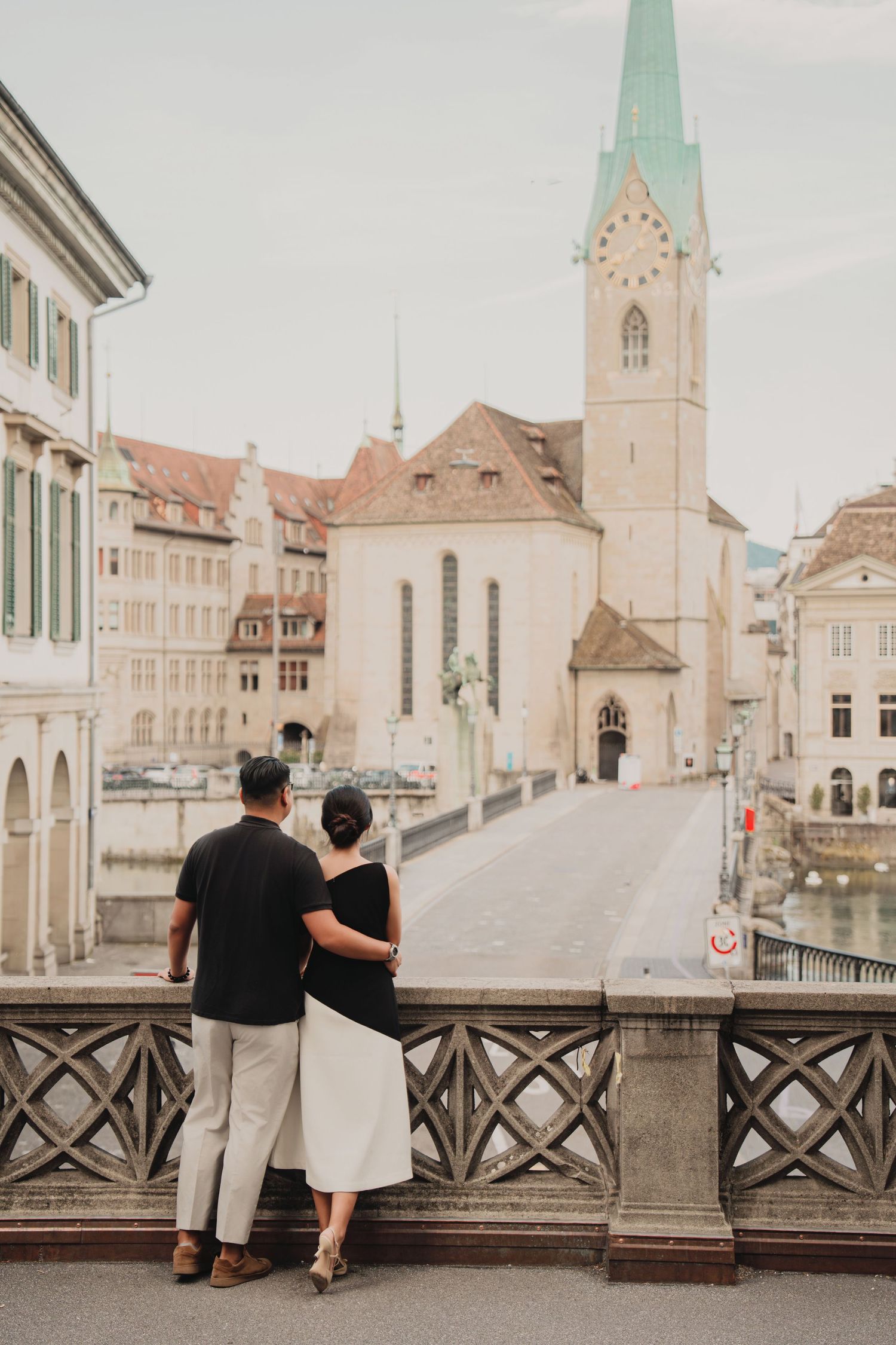 Romantic couple embracing on a bridge overlooking Fraumunster Church in Zurich, Switzerland.