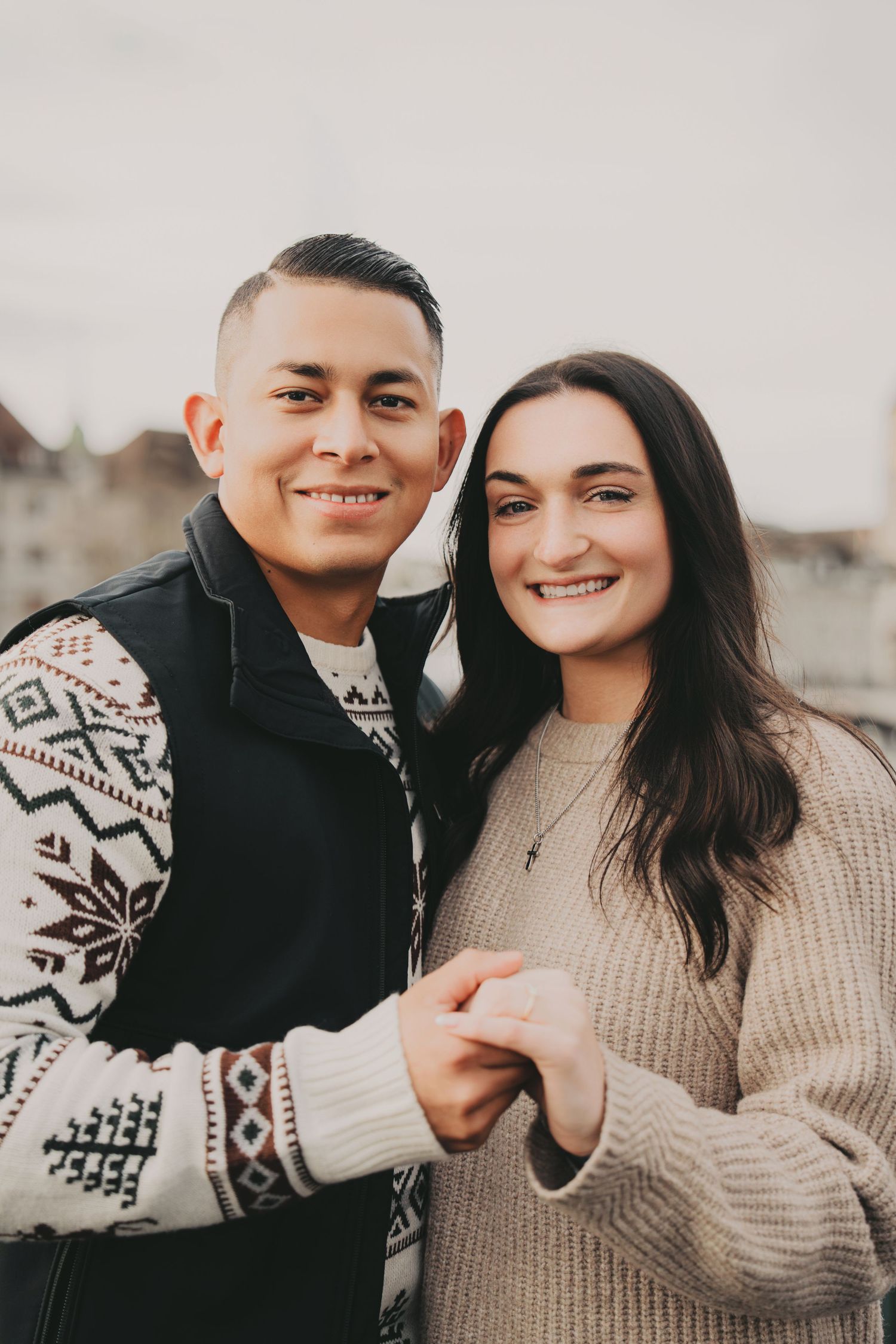 Smiling couple holding hands together with Zurich old town skyline in background.