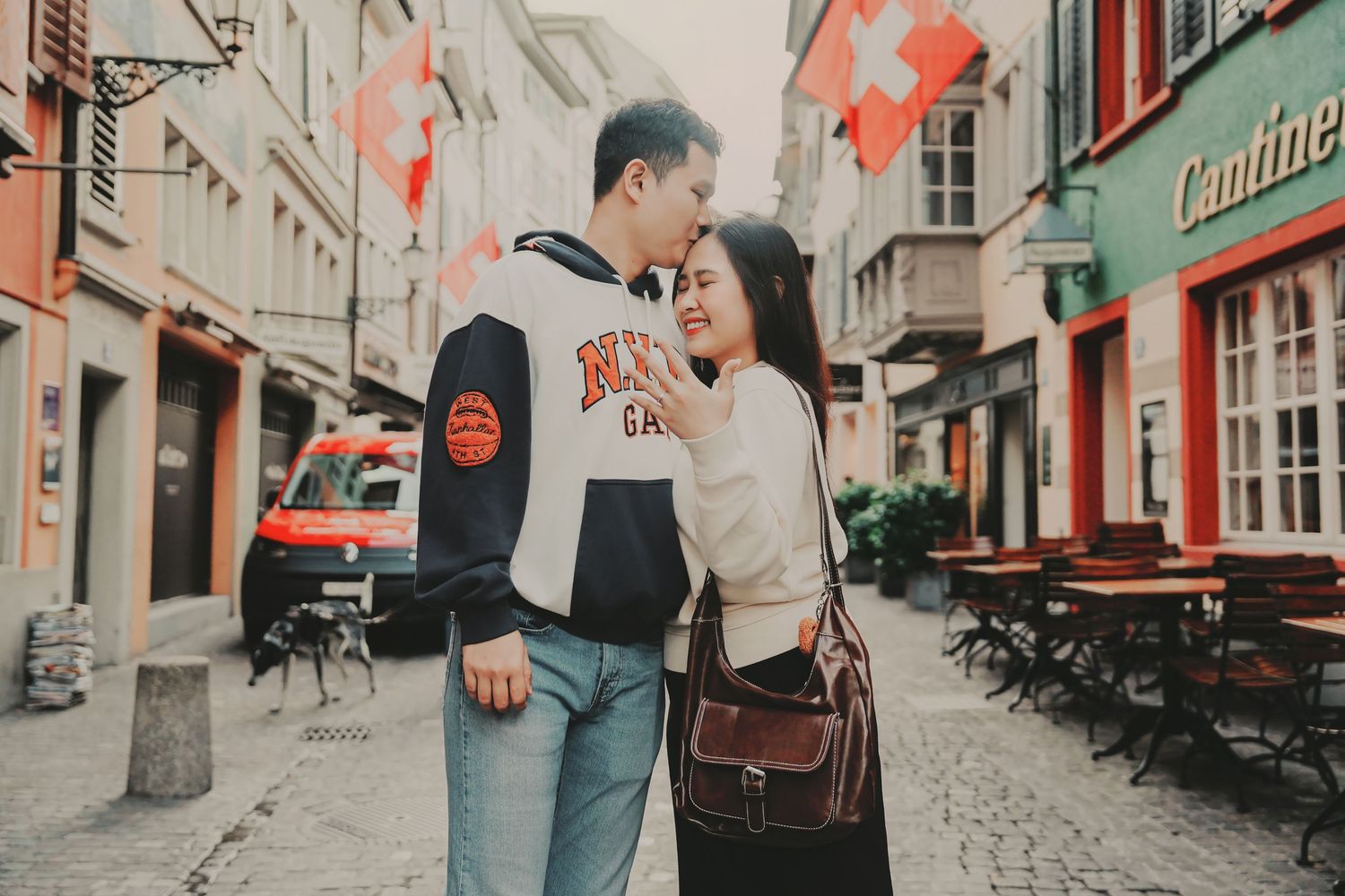 Romantic couple standing close together on a picturesque Swiss old town street with colorful buildings.