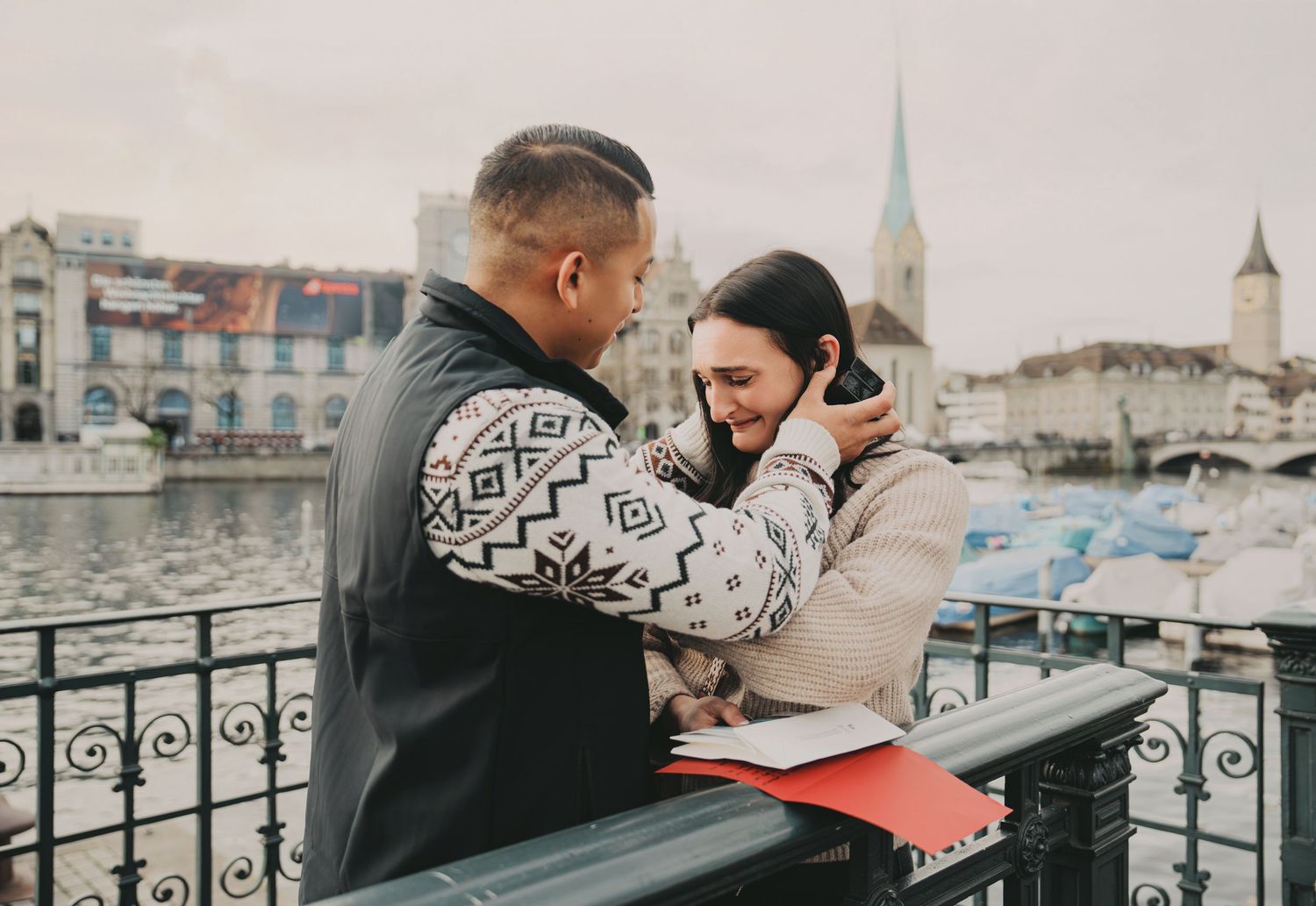 Couple sharing a romantic moment on a bridge overlooking Zurich's river and historic skyline.