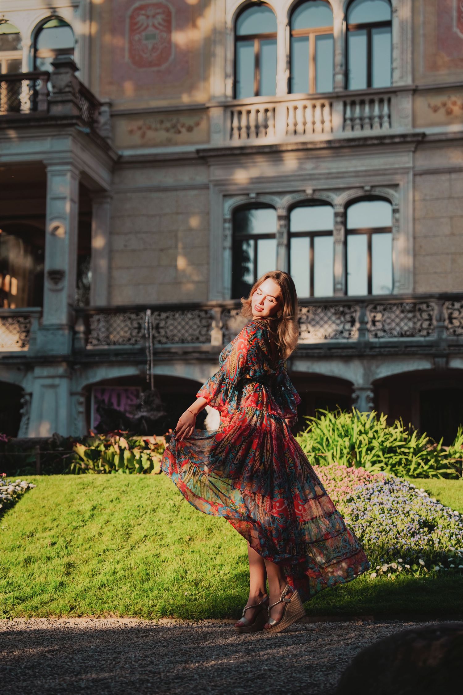 Woman in floral maxi dress posing in front of historic European building.