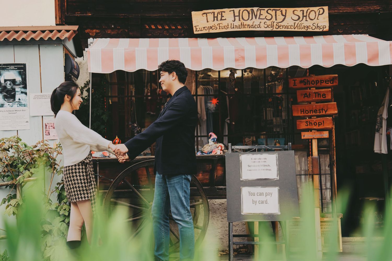 Couple holding hands outside The Honesty Shop vintage storefront with striped awning.