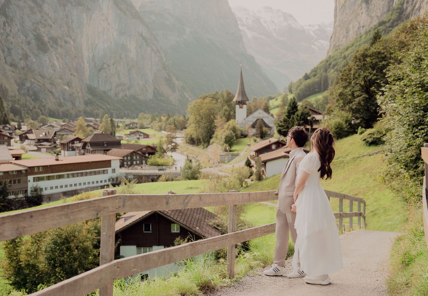 Couple embracing on a wooden bridge overlooking the picturesque Lauterbrunnen valley in Switzerland.