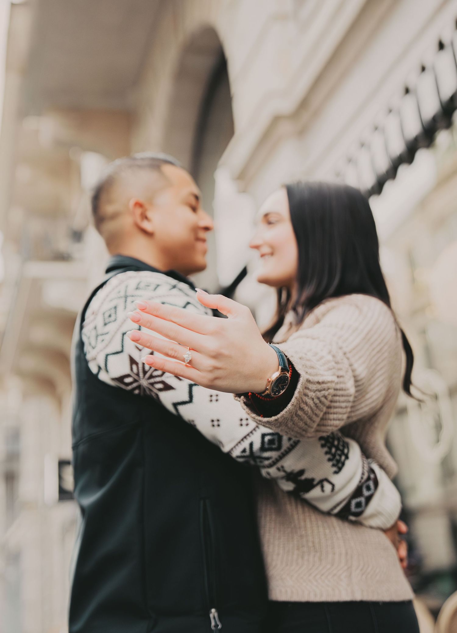 Close-up of smiling couple embracing each other in front of a European building.