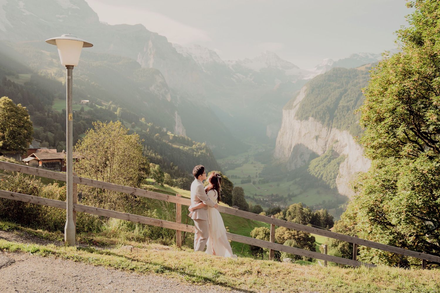 Romantic couple kissing near a lamppost with sweeping Lauterbrunnen valley views in Switzerland.