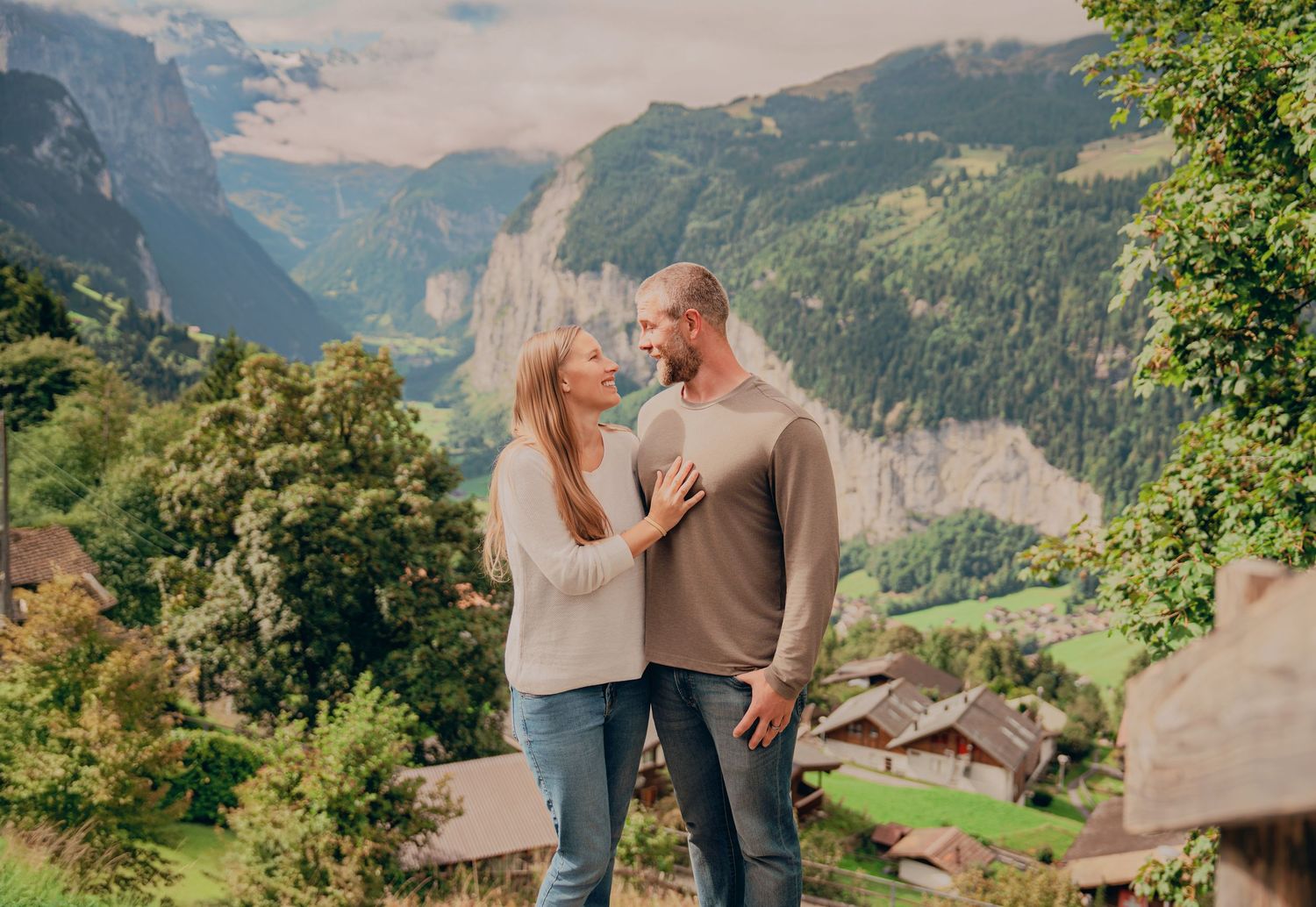 Romantic couple gazing at each other with stunning Swiss Alps valley backdrop.