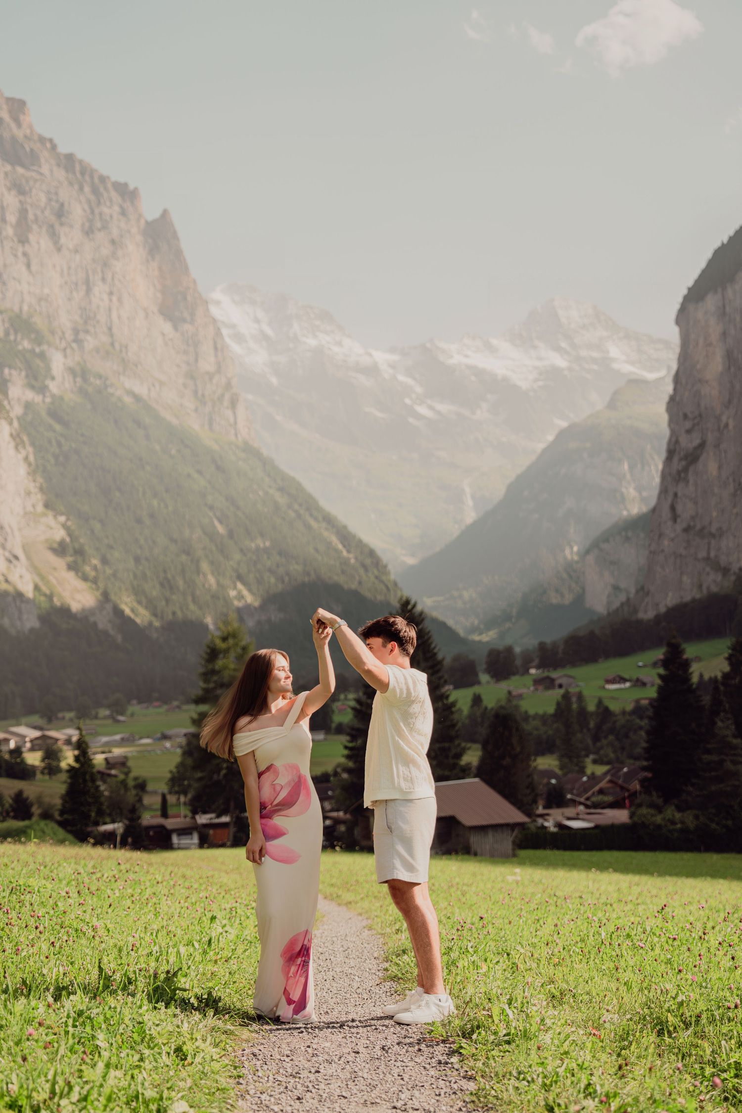 Couple dancing on a mountain path in Lauterbrunnen valley, Switzerland, with snow-capped peaks backdrop.