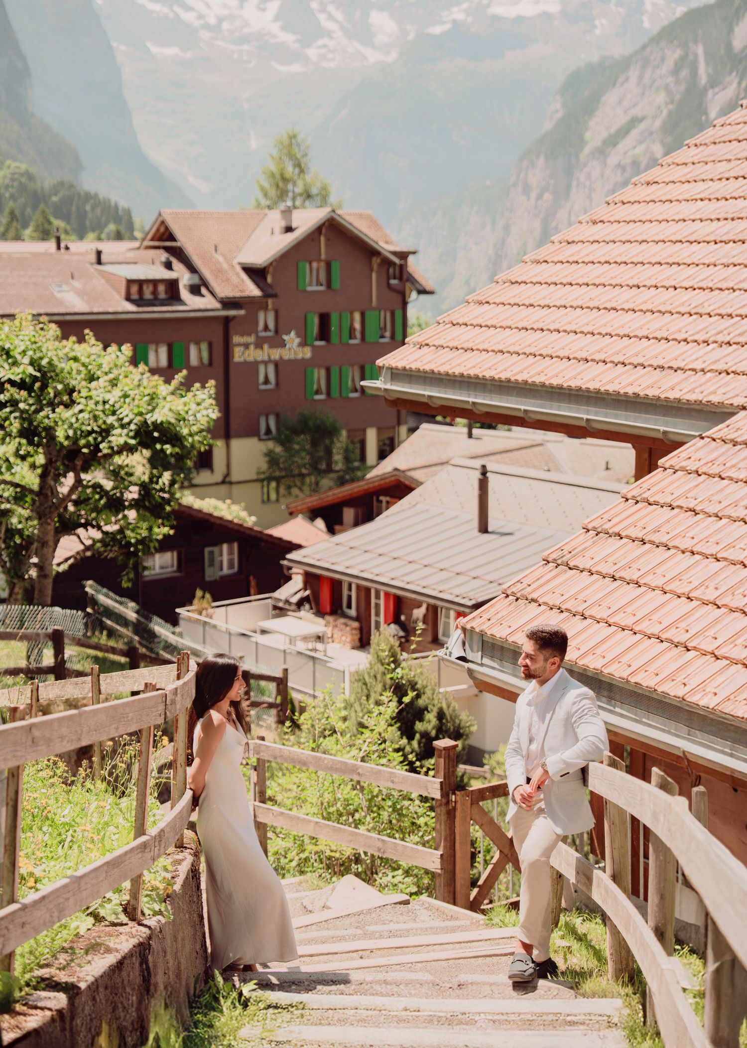 Bride and groom walking down wooden stairs beside traditional Swiss chalet buildings in Wengen.
