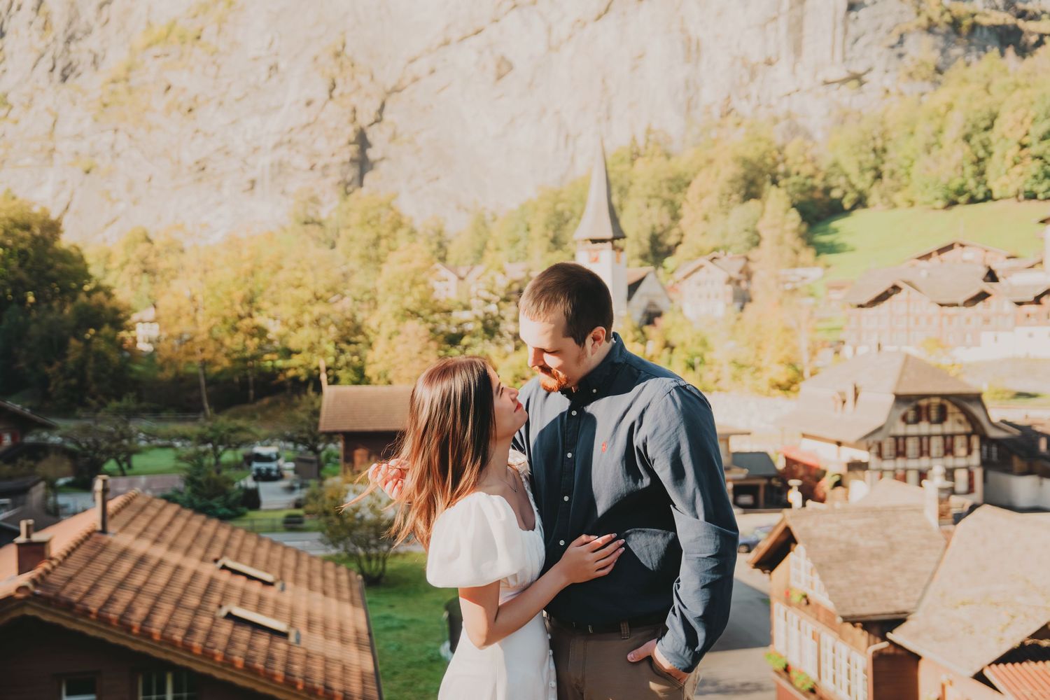 Couple sharing a romantic moment on a balcony overlooking a charming Swiss village.
