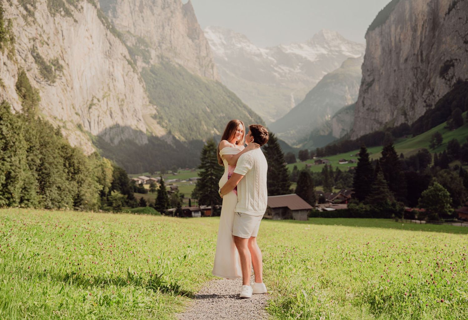 Couple sharing a kiss on a scenic mountain path in Lauterbrunnen, Switzerland, surrounded by Alps.