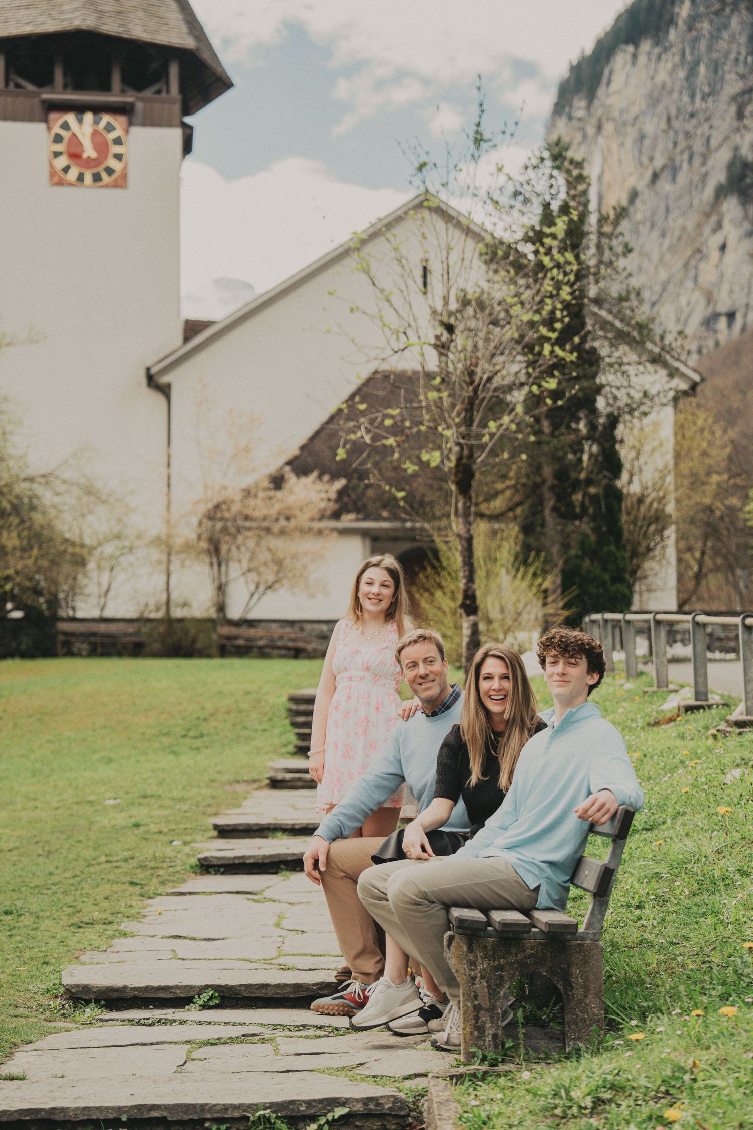 Family sitting and standing near a historic Swiss church with a decorative clock tower.