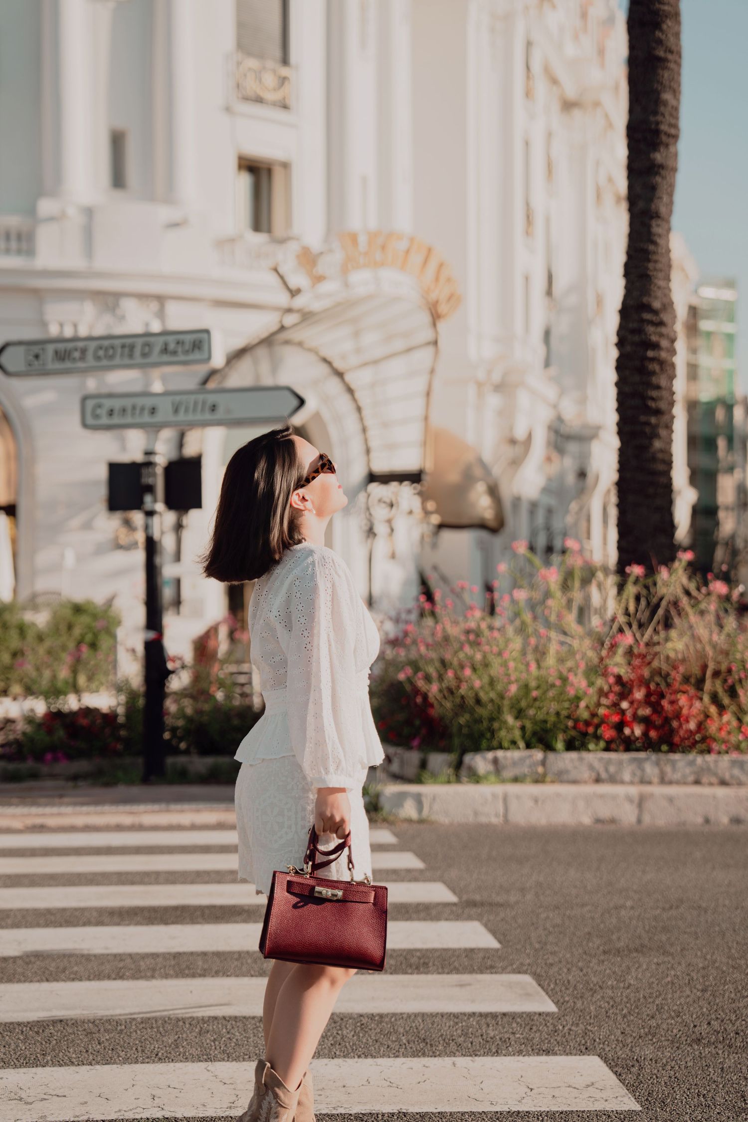 Woman in white dress crossing street near Le Negresco hotel in Nice, Cote d Azur.