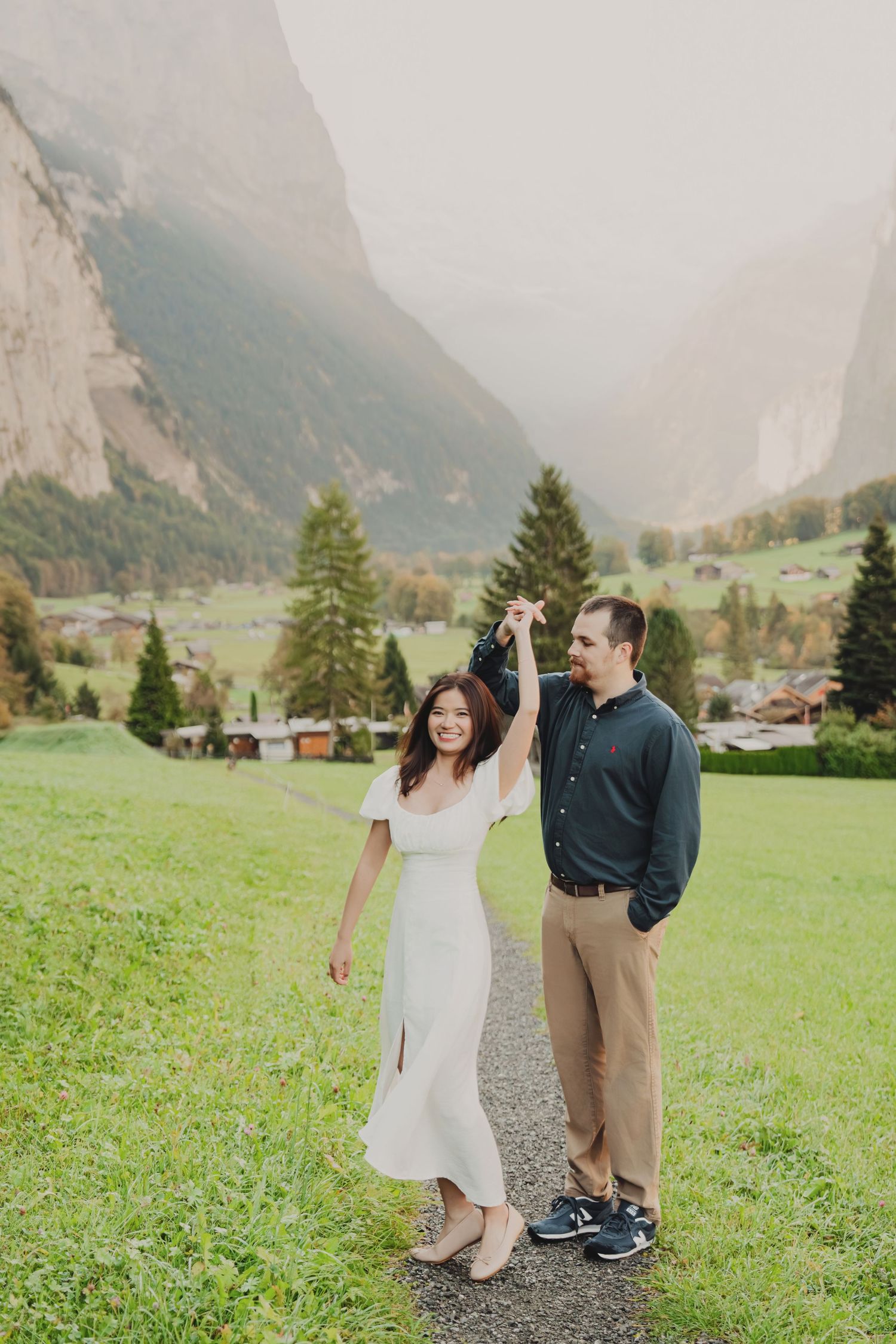 Couple dancing on a path with stunning Swiss alpine valley and mountains behind them.
