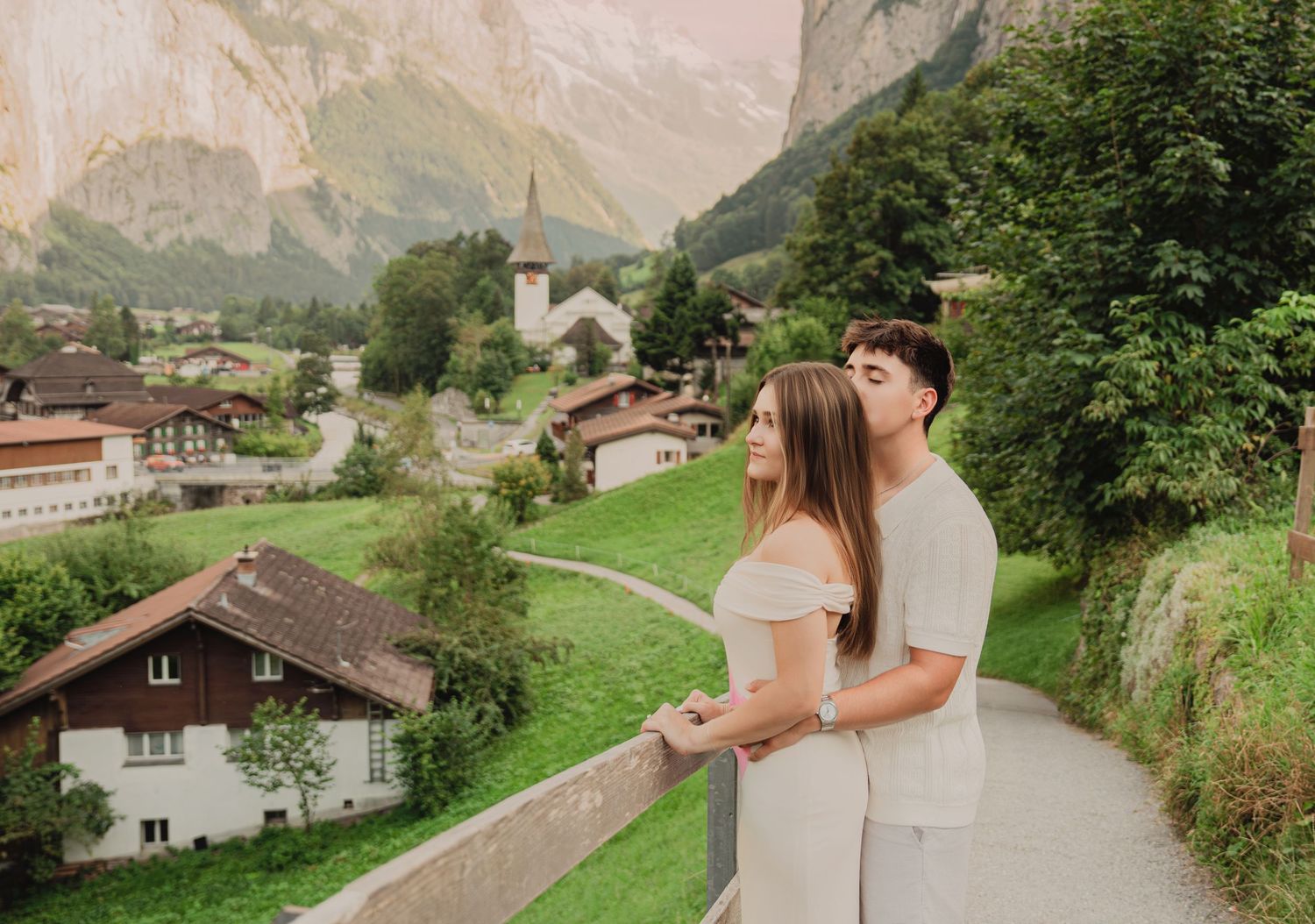Couple gazing at the picturesque Swiss village of Lauterbrunnen from a scenic mountain viewpoint.