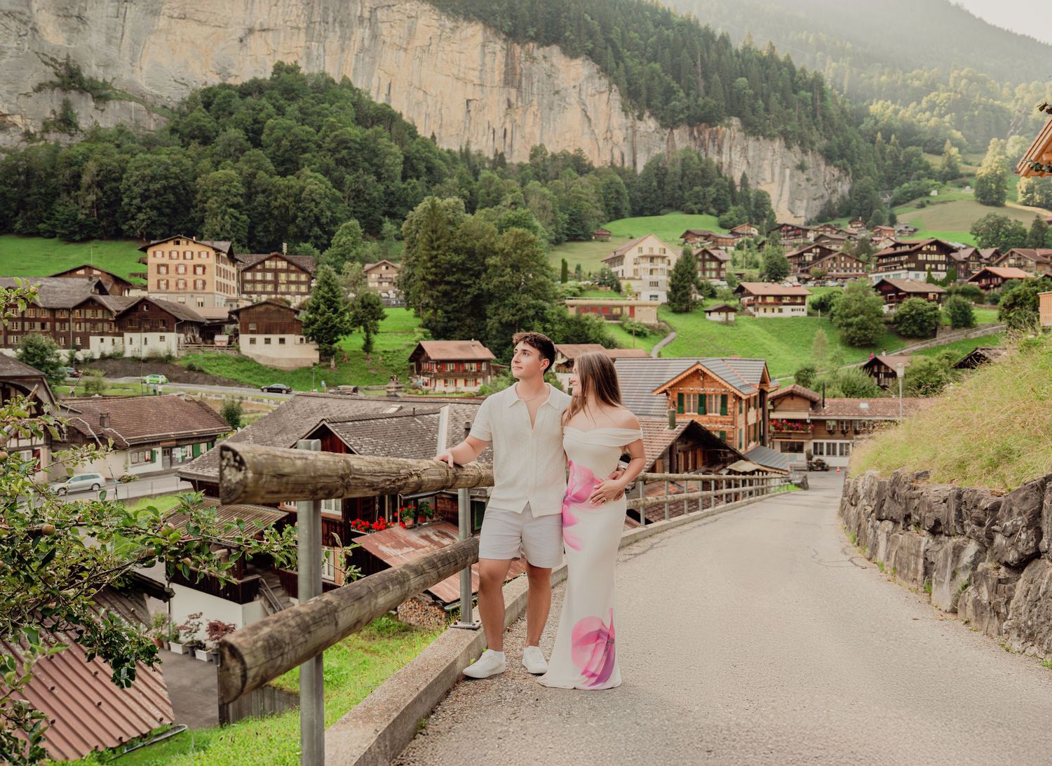 Couple standing at a wooden railing overlooking the stunning alpine village of Lauterbrunnen Switzerland.