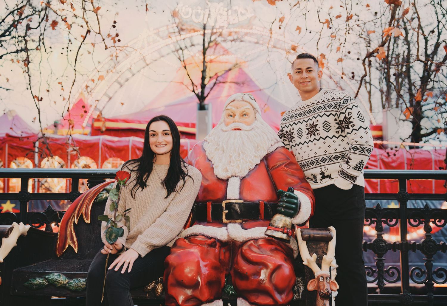 Couple posing with Santa Claus decoration at colorful Zurich Christmas market fairground.