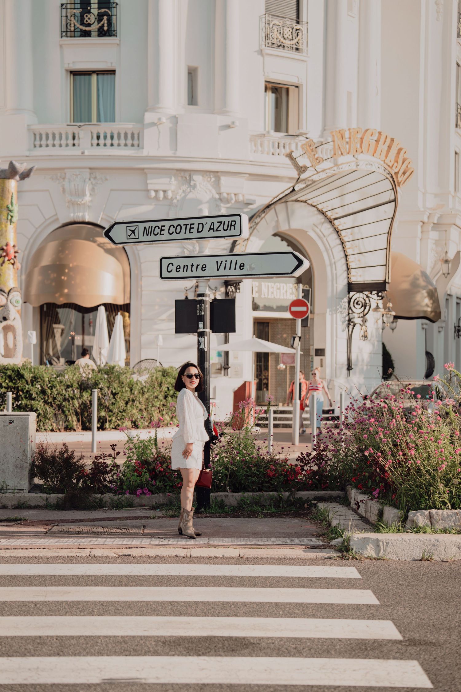 Woman in white dress standing near Centre Ville sign outside Le Negresco hotel in Nice.