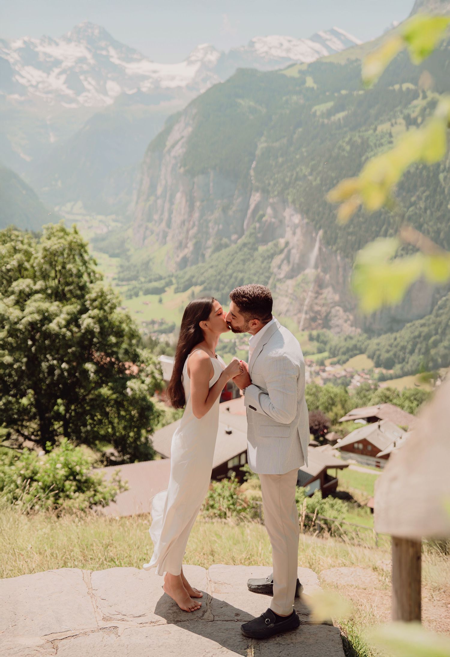 Couple sharing a romantic kiss during their Alpine elopement with snowy mountain peaks behind.