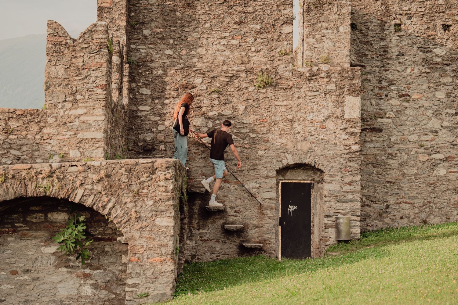 Couple climbing stone stairs of an ancient castle ruins on a sunny day.