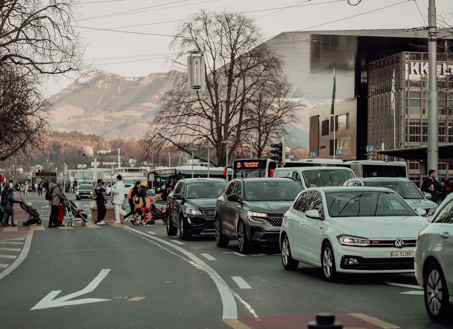 Traffic jam on urban road with mountains and IKEA store in background.