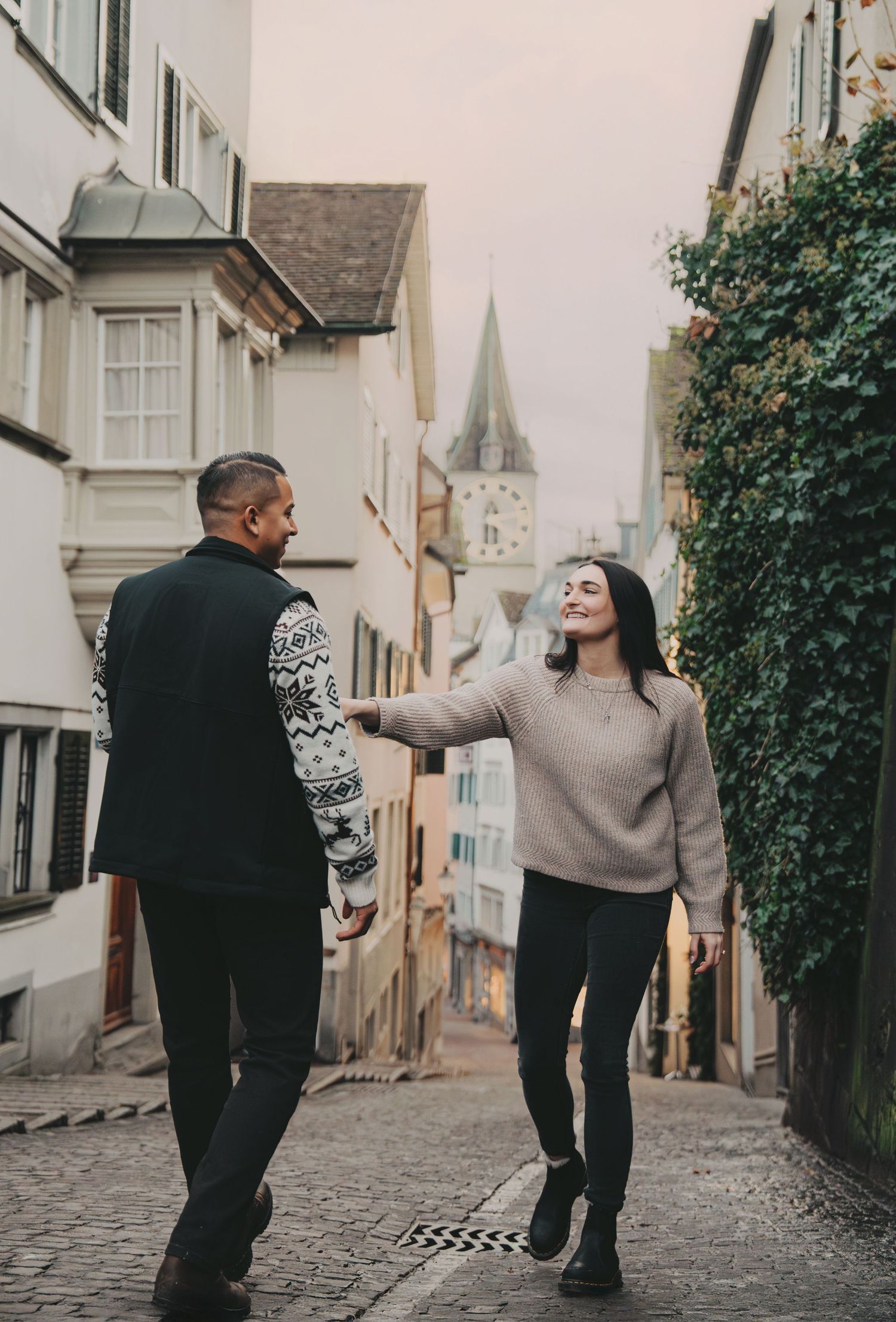 Happy couple holding hands walking down a picturesque European old town alley.
