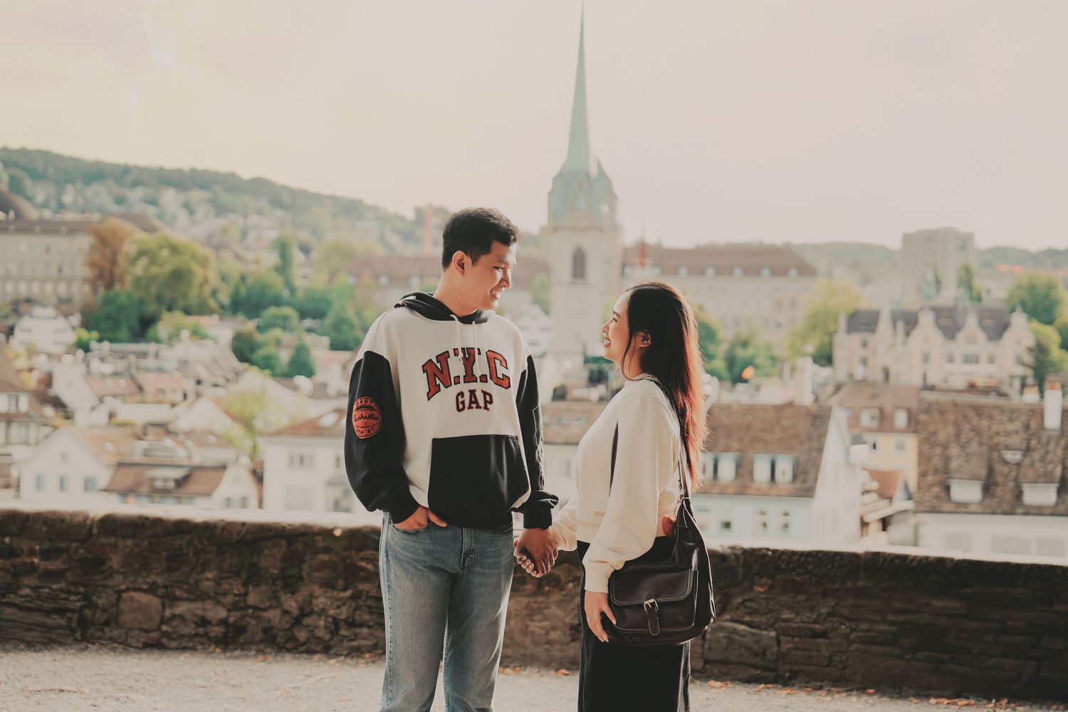 Couple holding hands and talking on a terrace overlooking Zurich's historic skyline with church spires.