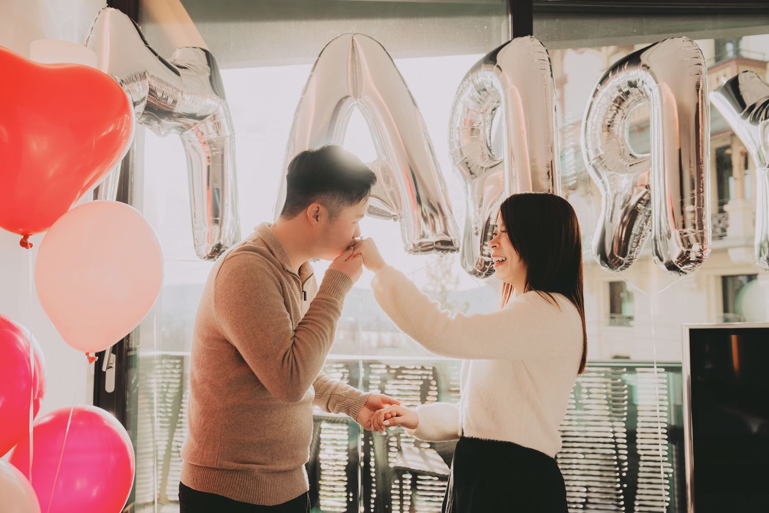 Asian couple sharing a romantic moment during a marriage proposal surrounded by colorful balloons.