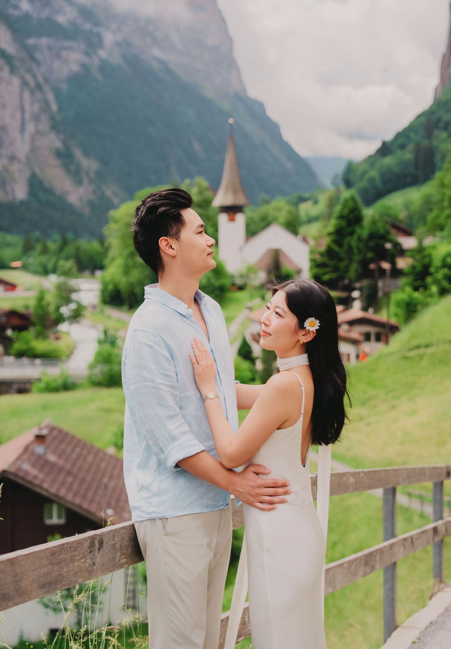 Couple shares a tender moment on a balcony overlooking the charming village of Lauterbrunnen, Switzerland.