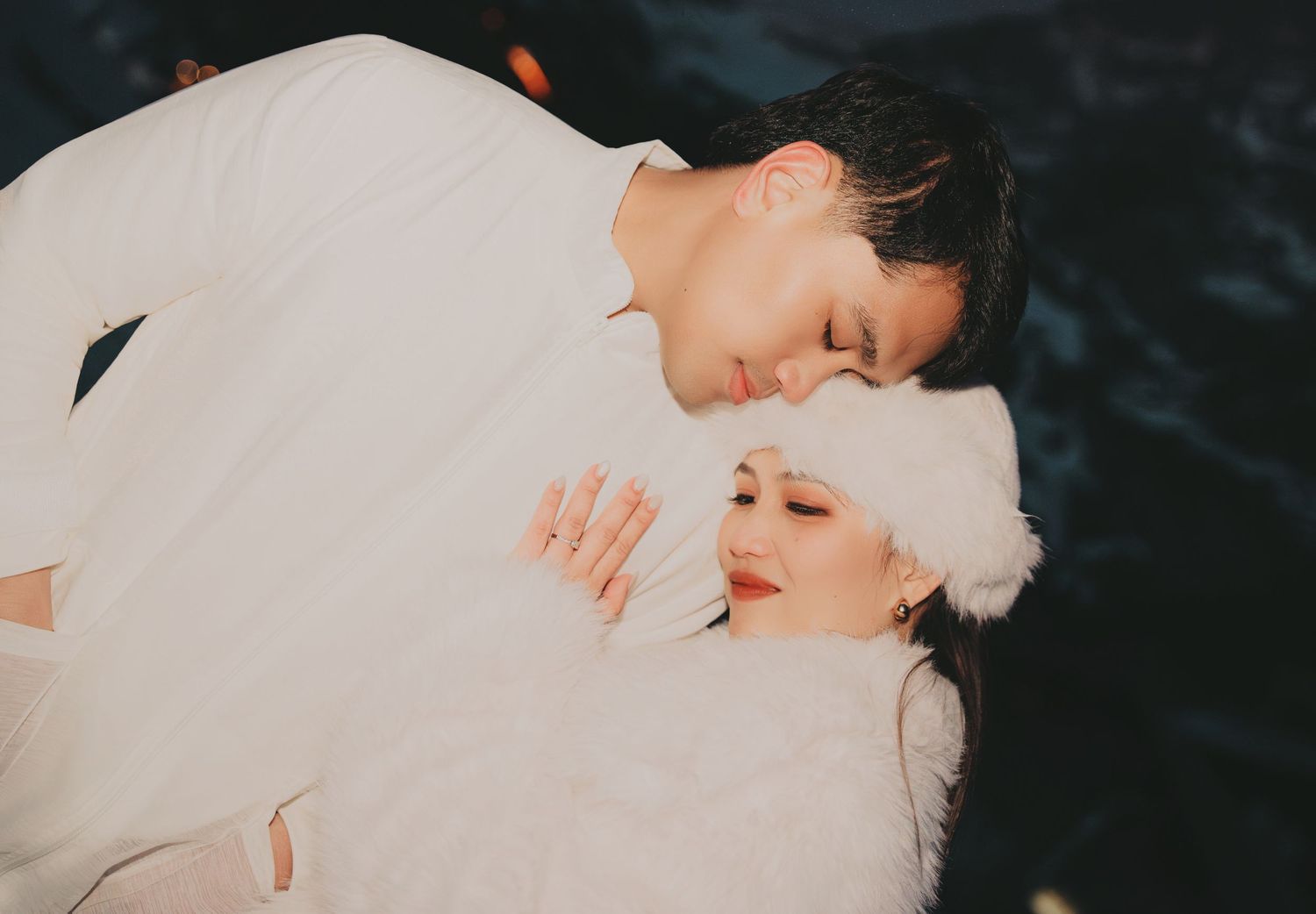 Intimate close-up of couple in white winter outfits sharing a tender moment.